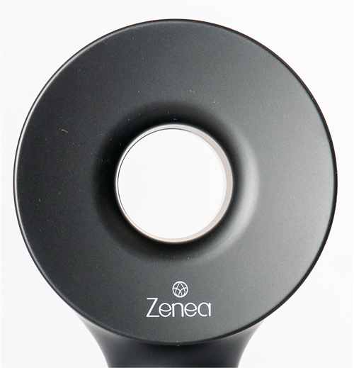 Detail čiernej filtračnej sprchovej hlavice Zenea so stredovým otvorom a logom na bielom pozadí