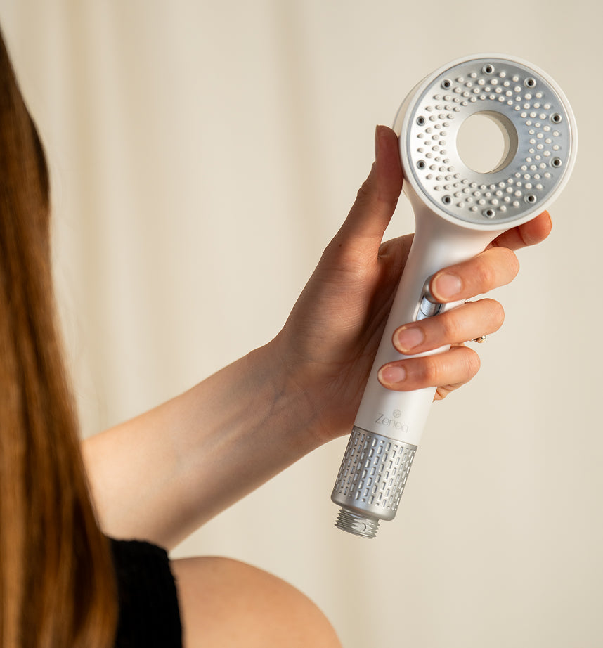 Žena drží filtrační sprchovou hlavici Zenea s ACF filtrem na odstranění chlóru a nečistot z vody pro zdravější pokožku a vlasy